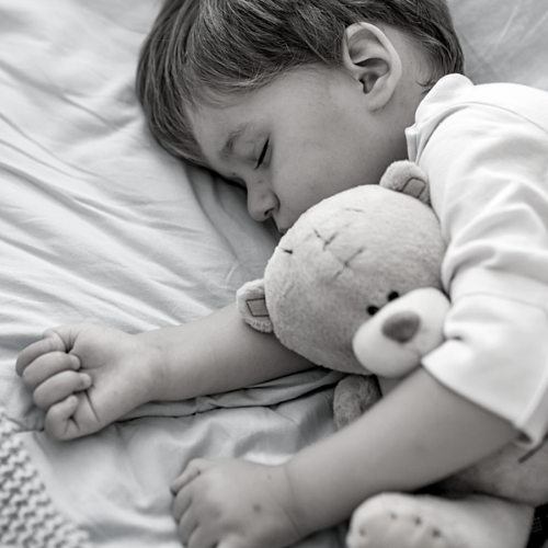 Child asleep cuddling teddy